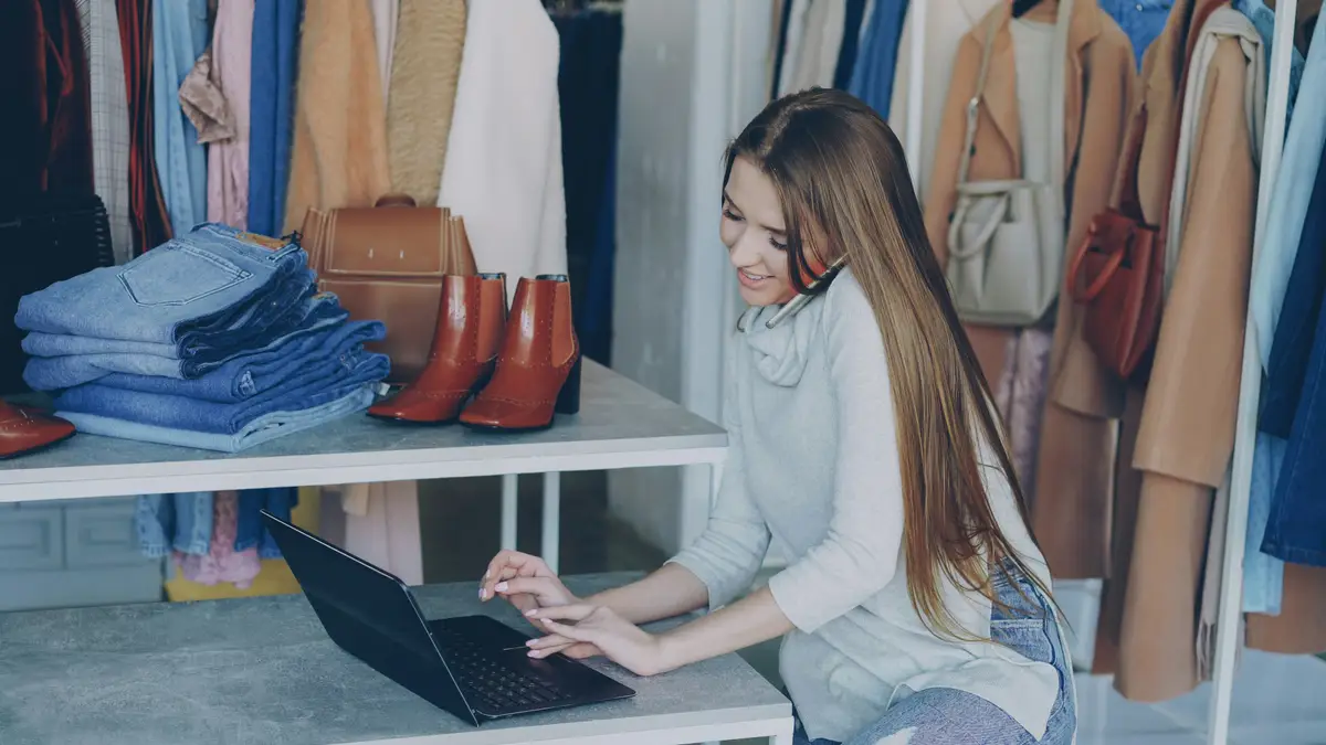 A shop owner working on her laptop by the counter.