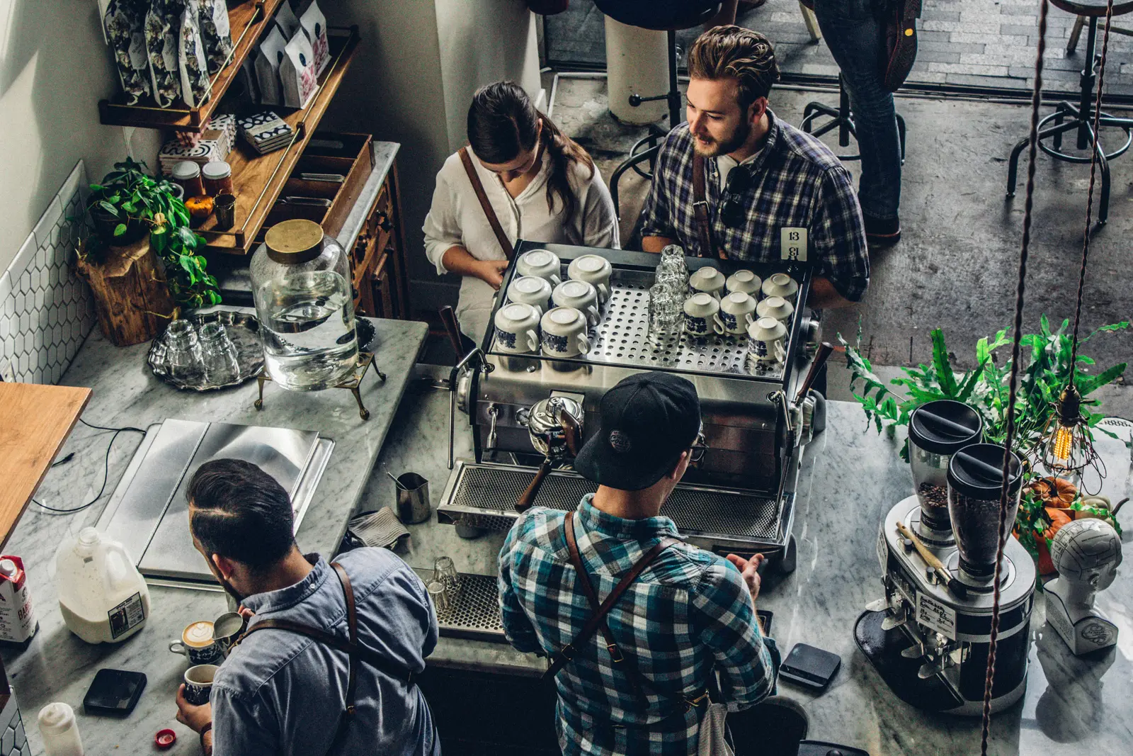 Equipo de una cafetería trabajando en la barra durante un turno ocupado.