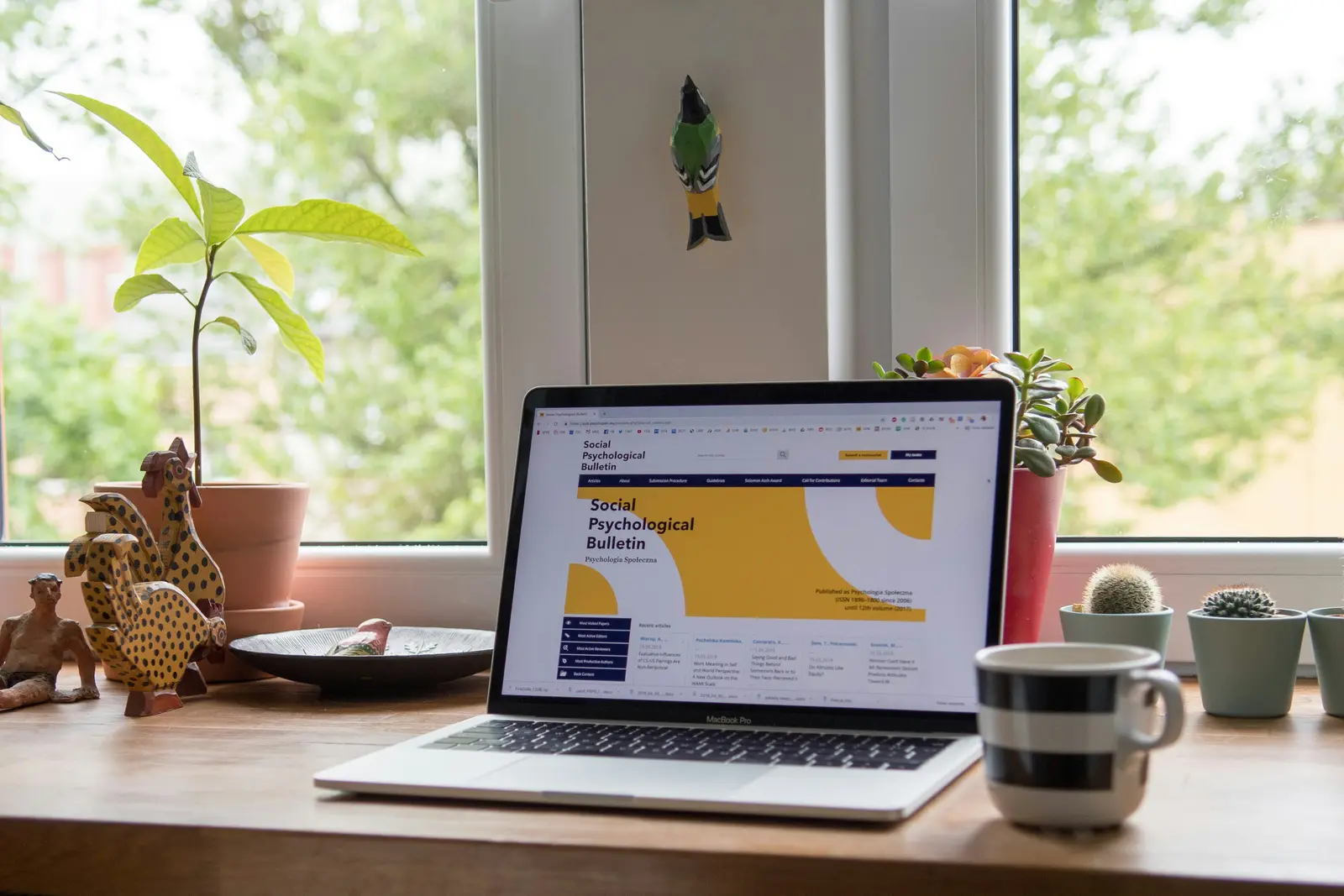 An open laptop showing a work dashboard on a desk by the window.